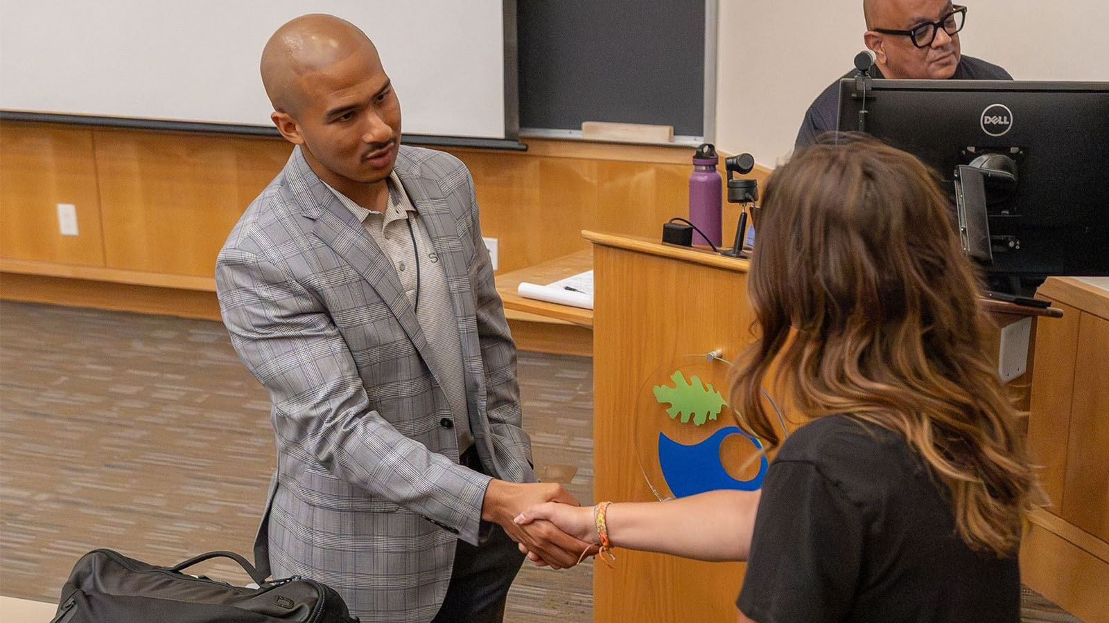 USF alumnus Morris Thomas in business attire shaking someone's hand