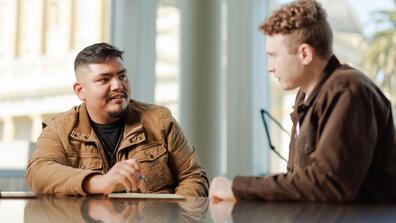 Two law students seated at a table, chatting about a project