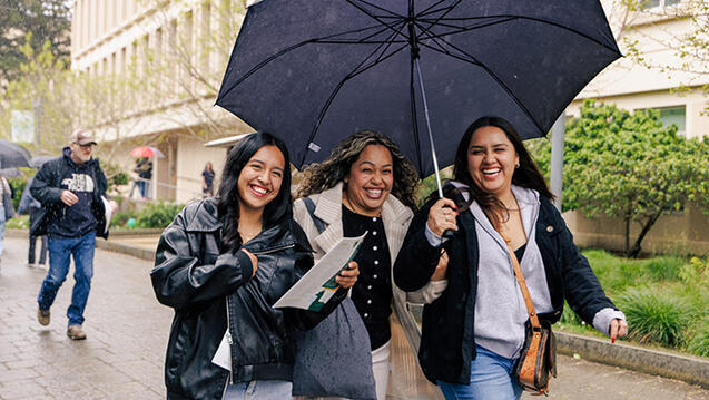 Students walking on campus sharing an umbrella on a rainy day