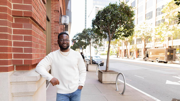 Man standing outside building leaning 