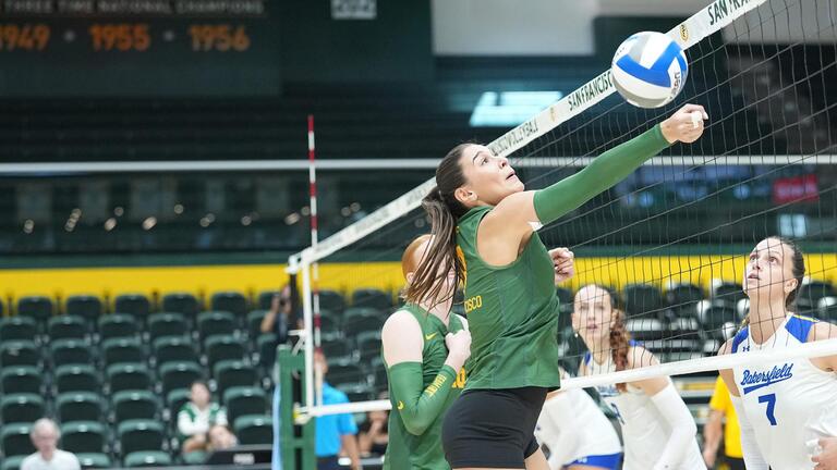 volleyball player hits ball over net
