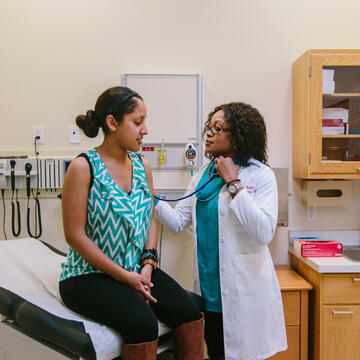 nursing student in scrubs holds stethoscope