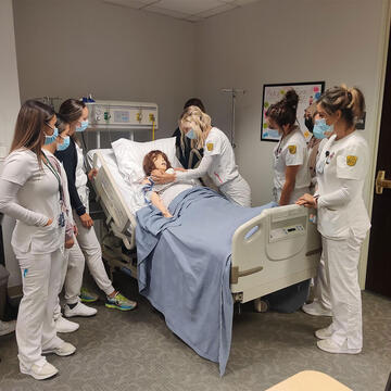 group of nursing students interact with manikin