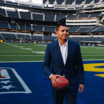 Sport Management student on a field holding a football