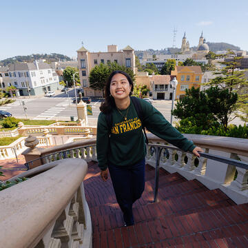 USF student smiling while climbing Lone Mountain steps