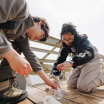 students performing experiment by the water