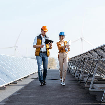 Two people walking near solar panels.