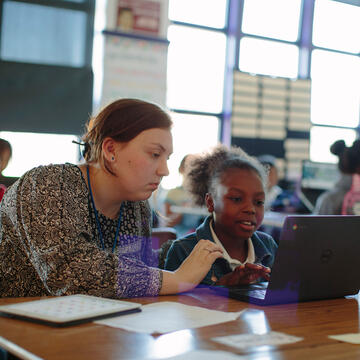 USF grad student helping young student on laptop