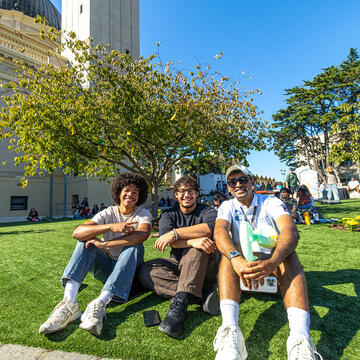 three students sit on lawn during celebrate usf