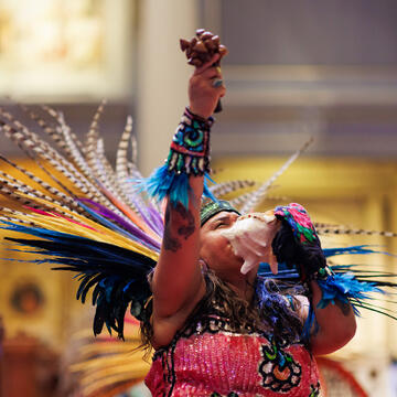 performer blows into shell during cultural center graduation cermony
